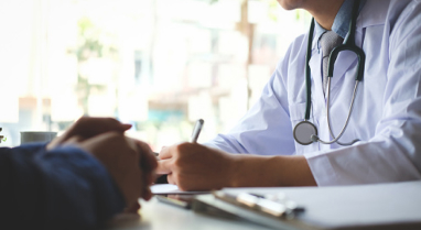 Doctor writing on clipboard across from patient