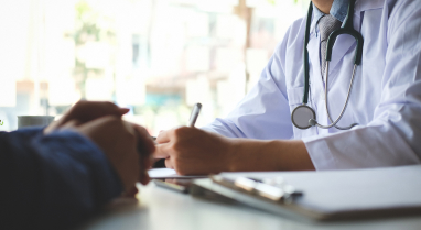 Doctor writing on clipboard across from patient